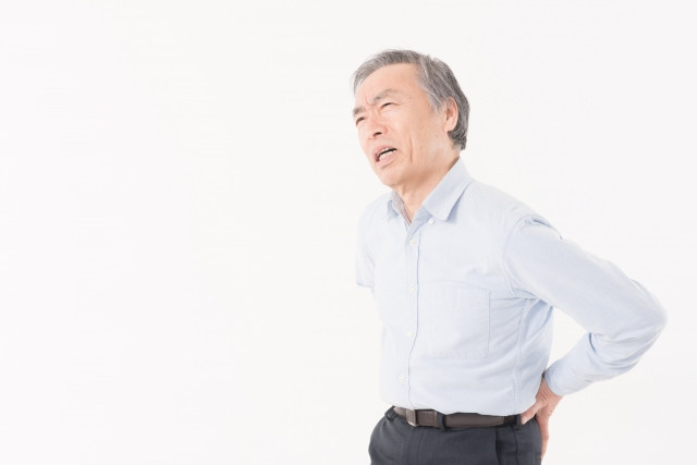 腰を抑える男性の写真